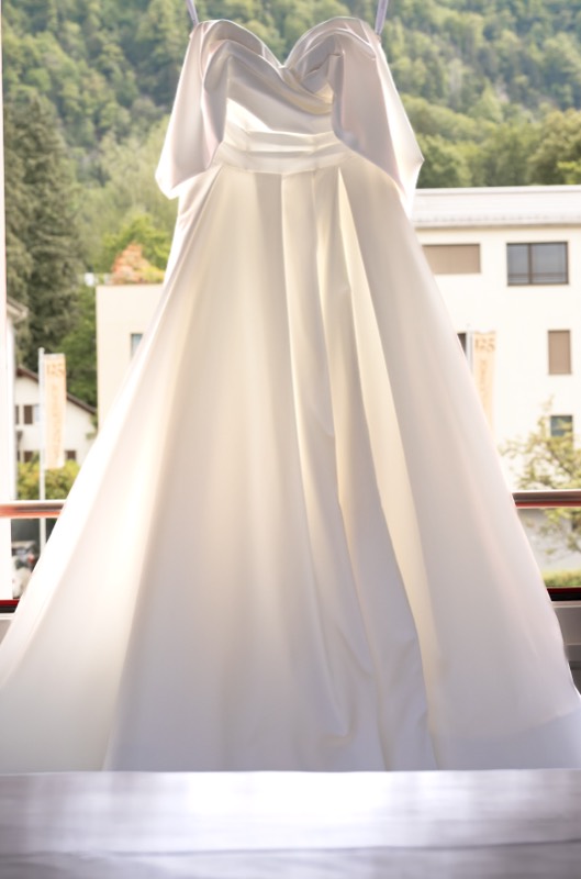 Brautkleid hängt vor einem hellen Fenster