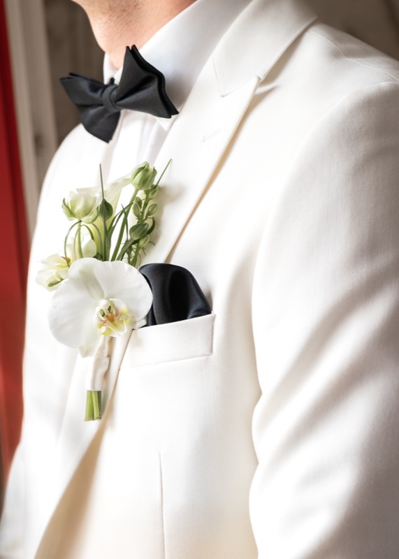 Weisses Jackett mit schwarzer Fliege und Ansteckblume