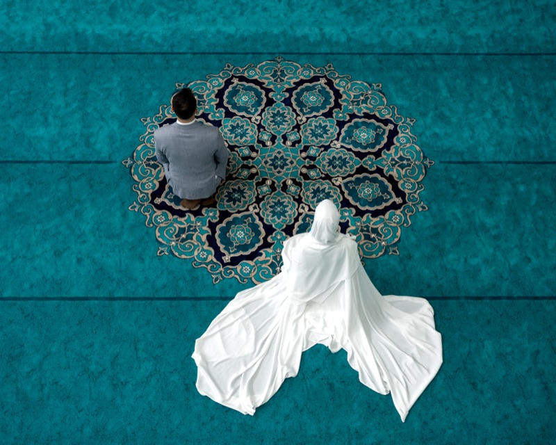 Brautpaar von oben auf einem türkisfarbenen Teppich mit Ornament