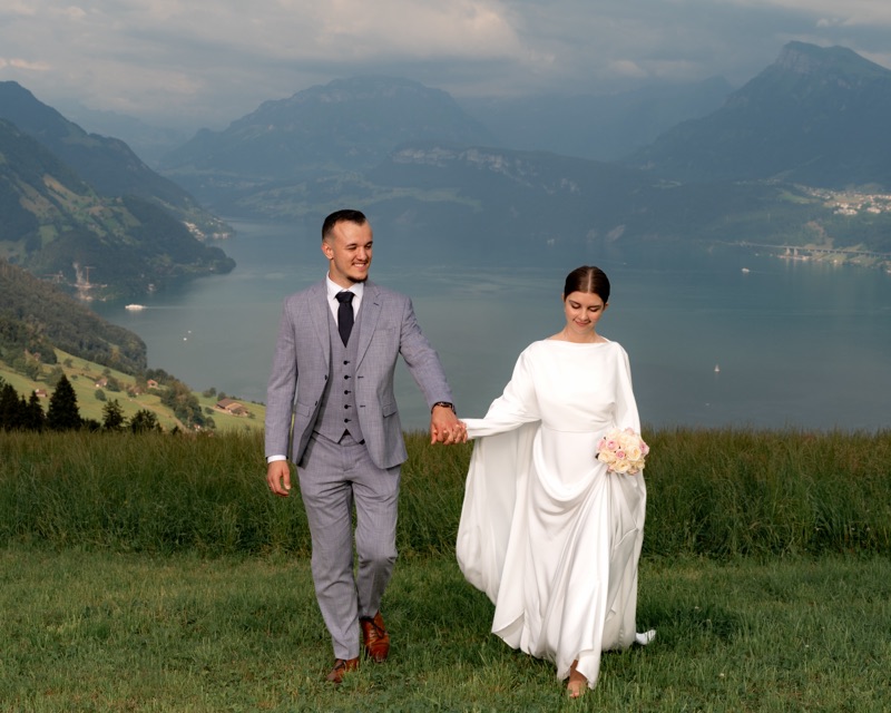Brautpaar geht Hand in Hand über eine Bergwiese