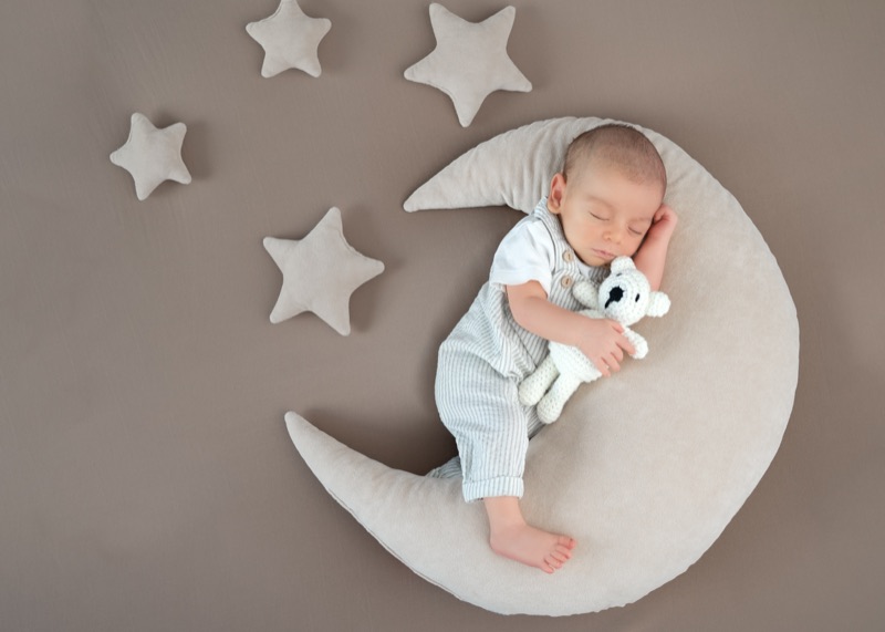 Baby schläft auf einem Mondkissen zwischen Stoffsternen