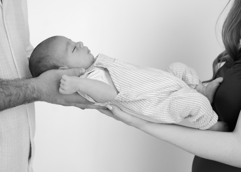 Eltern halten das Baby gemeinsam auf den Händen, schwarzweiss