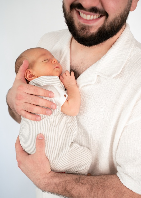 Vater hält sein schlafendes Baby im Arm und lacht