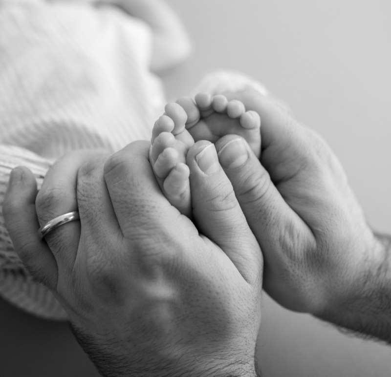 Babyfüsse in den Händen der Eltern, schwarzweiss