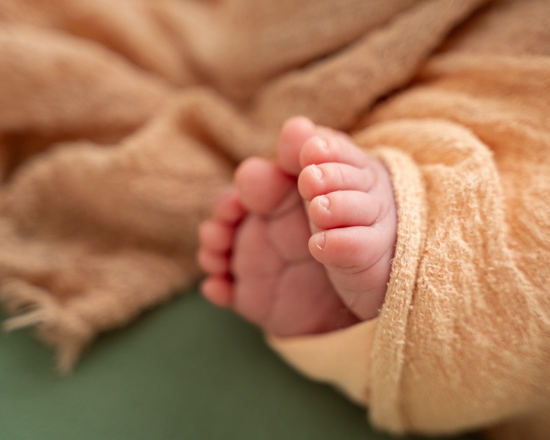Babyfüsse schauen aus einem pfirsichfarbenen Tuch