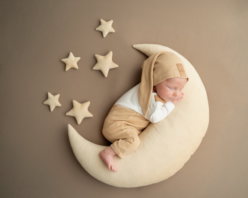 Baby mit Zipfelmütze schläft auf einem Mondkissen